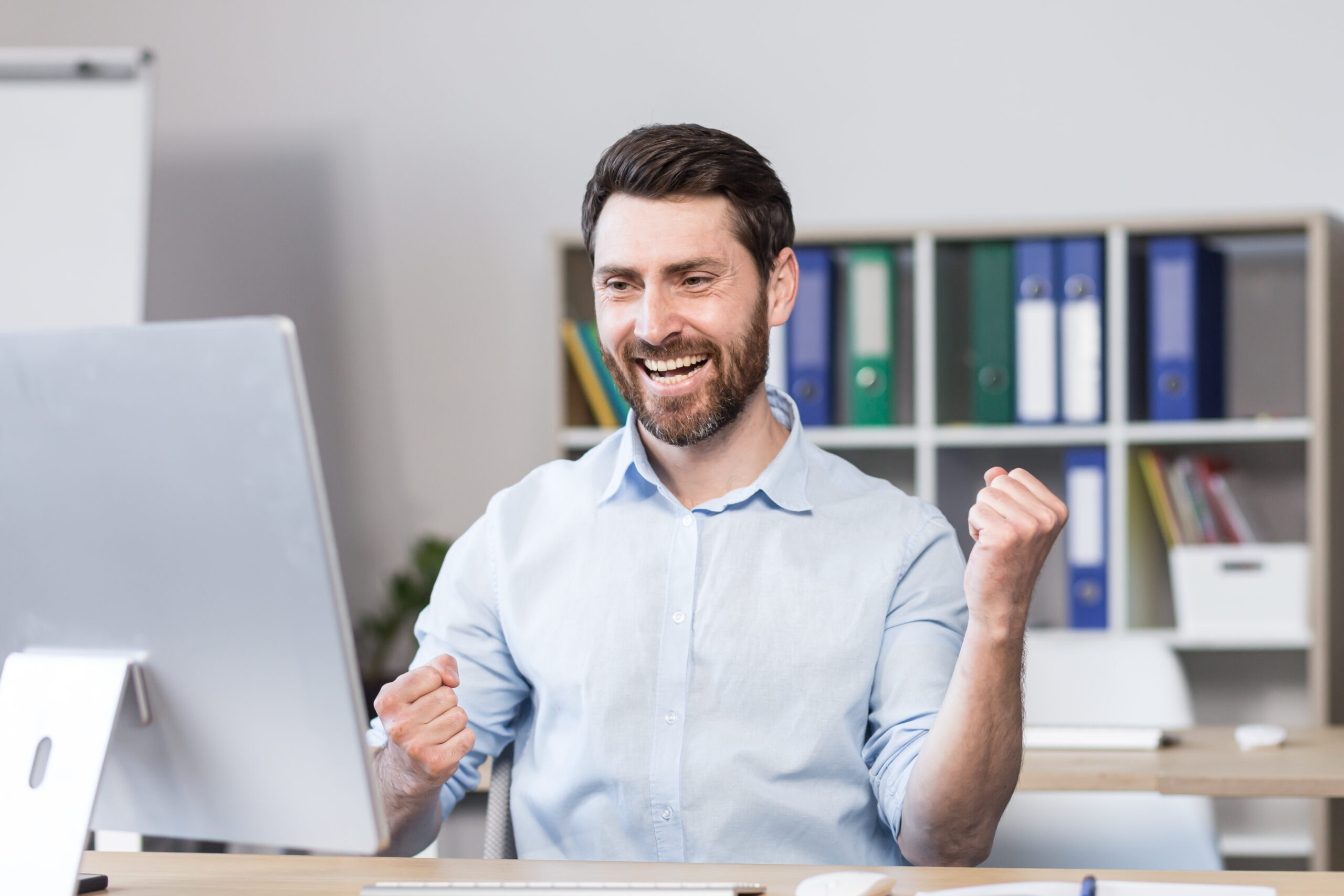 Young successful man, office worker, manager, freelancer rejoices in the result of the work